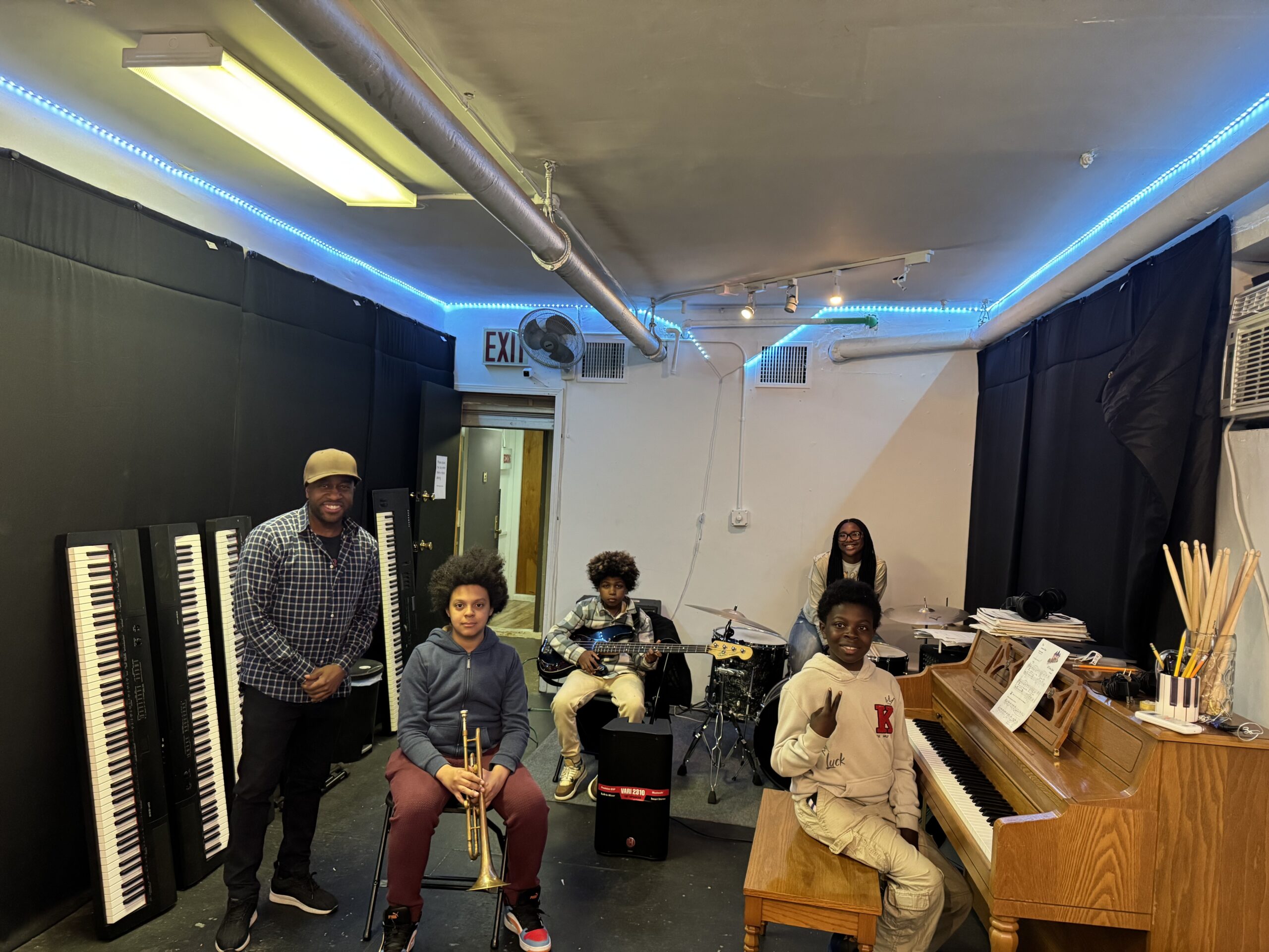 Instructor and young musicians with trumpet, bass, drums and piano at the Harlem Youth Music Workshop